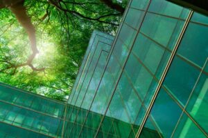 prédio de vidro refletindo o verde da natureza que o cerca