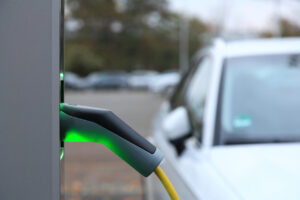 : Imagem mostra carro sendo abastecido eletricamente, conforme mostra a bomba de abastecimento conectada a ele.